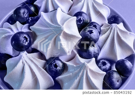 French berry meringue cookies or marshmallow and blueberries in the plate on the table close-up, Very Peri Color Of The Year 2022 French berry meringue cookies or marshmallow and blueberries in the plate on the table close-up, Very Peri Color Of The Year 2022 85043192