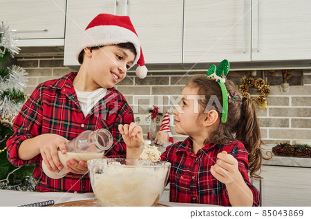 Beautiful European children enjoying time together, having fun while kneading dough, cooking cookies and bakeries, helping their mother at home kitchen. Christmas and happy childhood concept 85043869