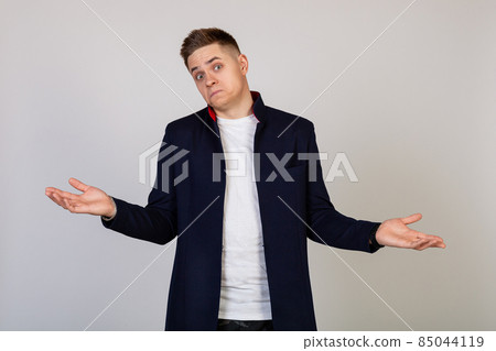Male young man with a lost expression shrugs his shoulders. The guy spreads his hands and does not 85044119