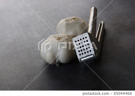 Garlic press and garlic on a concrete pattern background Garlic press and garlic on a concrete pattern background 85044468
