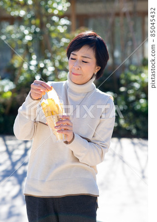 Journey Women's Journey A woman eating sweet potato chips in Little Edo Kawagoe Journey Women's Journey A woman eating sweet potato chips in Little Edo Kawagoe 85045432