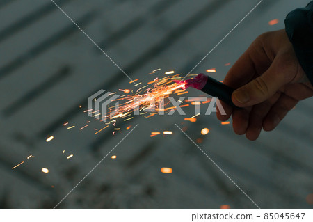 Burning Firecracker with Sparks. Guy Holding a Petard in a Hand Burning Firecracker with Sparks. Guy Holding a Petard in a Hand 85045647
