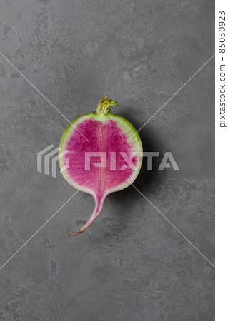Half Lobo Margelian radish with a pink center. Close-up on a gray background. Vertical with space. 85050923