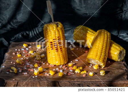 Grilled corn on the cob  on rustic wooden board  over dark background. 85051421