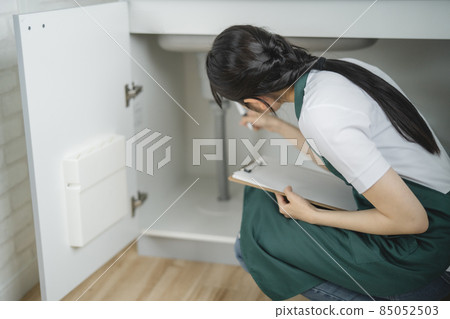 Female checking the water supply (under the sink) 85052503