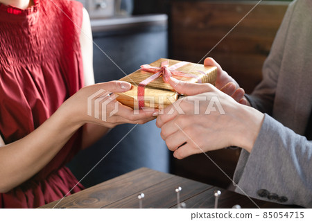 Couple date at the hands of a man giving a present Couple date at the hands of a man giving a present 85054715