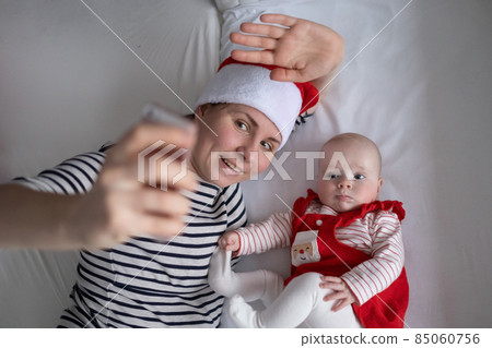 Loving young mommy making a selphie with a adorable sweet baby girl lying in bed. Loving young mommy making a selphie with a adorable sweet baby girl lying in bed. 85060756