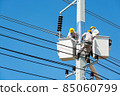 Group of Male Engineer or Electrician working on Crane Bucket over Electrical Pole 85060799