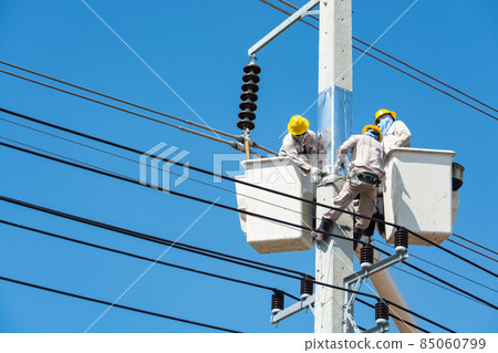 Group of Male Engineer or Electrician working on Crane Bucket over Electrical Pole Group of Male Engineer or Electrician working on Crane Bucket over Electrical Pole 85060799