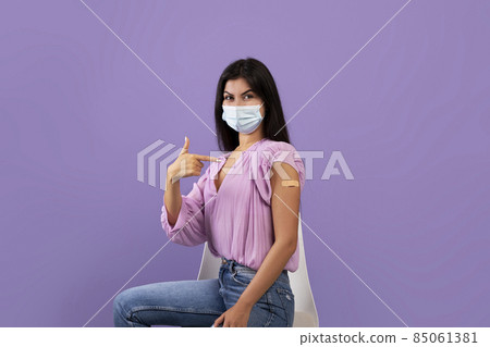 Armenian lady having vaccination in clinic, wearing protective face mask, showing thumb up while sitting on chair 85061381