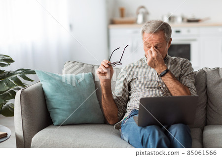 Senior Man Taking Off Glasses After Work On Laptop Indoor 85061566