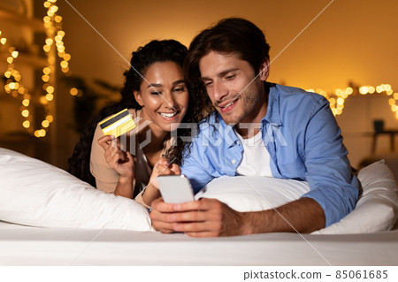 Spouses Enjoying Online Shopping Using Cellphone And Credit Card Indoor 85061685