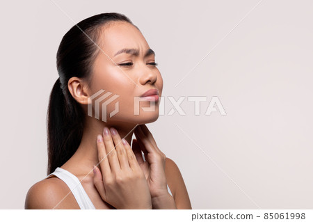 Asian woman suffering from sore throat, touching her neck Asian woman suffering from sore throat, touching her neck 85061998