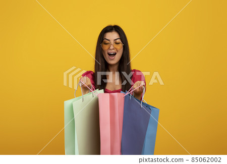 Satisfied customer. Excited armenian woman looking inside bright shopping bags, happy with her purchases Satisfied customer. Excited armenian woman looking inside bright shopping bags, happy with her purchases 85062002