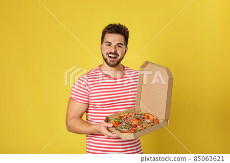 Handsome man with tasty pizza on yellow background 85063621