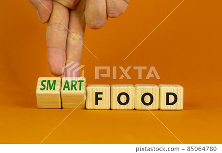 Smart food symbol. Doctor turns cubes and changes words 'food' to 'smart food'. Beautiful orange background. Medical, smart food concept. Copy space. 85064780