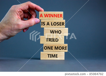 Winner or loser symbol. Wooden blocks with words A winner is a loser who tried one more time. Beautiful grey background, copy space. Businessman hand. Business, winner or loser concept. 85064782