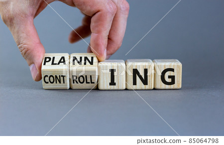 Planning or controlling symbol. Male hand flips wooden cubes and changes words 'planning' to 'controlling'. Beautiful grey background, copy space. Business and planning or controlling concept. 85064798