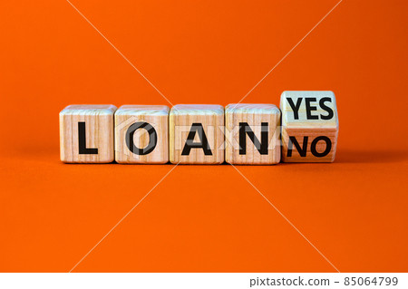 Loan yes or no symbol. Turned a wooden cube and changed words loan no to loan yes. Beautiful orange table, orange background, copy space. Business and loan yes or no concept. 85064799