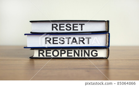 Books with text 'reset, restart, reopening' on beautiful wooden table. White background. Business concept. 85064866