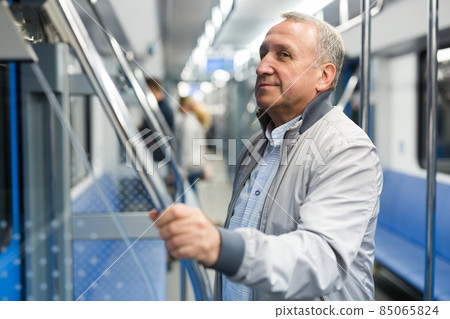 Mature man standing in subway and holding handrail Mature man standing in subway and holding handrail 85065824