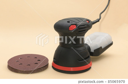 Eccentric orbital sander, with grinding wheels. grinder machine for wood with grinding wheel, close up. on a beige background. Eccentric orbital sander, with grinding wheels. grinder machine for wood with grinding wheel, close up. on a beige background. 85065970