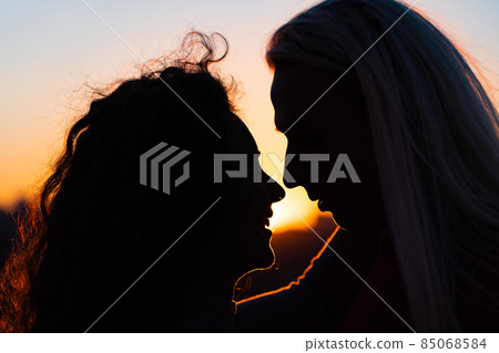 Silhouette of Romantic young couple kissing on sunset. Beginning of lovestory and relationship Silhouette of Romantic young couple kissing on sunset. Beginning of lovestory and relationship 85068584