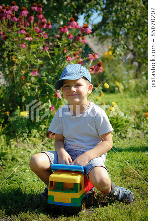 Boy playing outdoors with big toy car 85070202