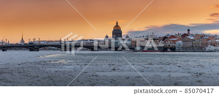 Winter panoramic view of St. Petersburg at sunset, Isaac cathedral and Blagoveshenskiy bridge on background, steam over frozen Neva river, huge ship moored near embankment, sky of orange color Winter panoramic view of St. Petersburg at sunset, Isaac cathedral and Blagoveshenskiy bridge on background, steam over frozen Neva river, huge ship moored near embankment, sky of orange color 85070417