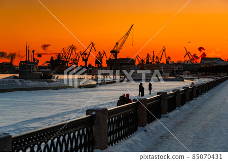 The construction of nuclear icebreakers at magic sunset, cranes of of the Baltic shipyard in a frosty winter day, steam over the Neva river, smooth surface of the river, sky of orange color The construction of nuclear icebreakers at magic sunset, cranes of of the Baltic shipyard in a frosty winter day, steam over the Neva river, smooth surface of the river, sky of orange color 85070431