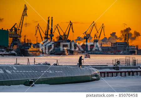 The construction of nuclear icebreakers at magic sunset, cranes of of the Baltic shipyard in a frosty winter day, steam over the Neva river, smooth surface of the river, sky of orange color 85070458