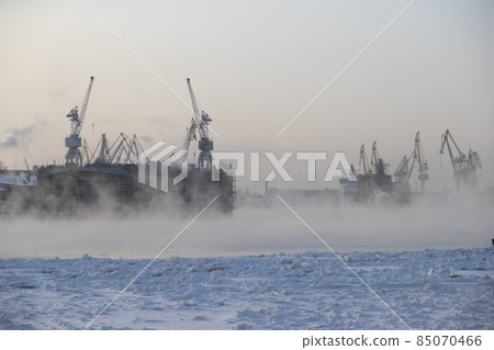 The construction of nuclear icebreakers, cranes of of the Baltic shipyard in a frosty winter day, steam over the Neva river, smooth surface of the river The construction of nuclear icebreakers, cranes of of the Baltic shipyard in a frosty winter day, steam over the Neva river, smooth surface of the river 85070466
