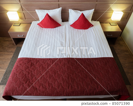 Beautiful bed with red pillows in the room 85071390