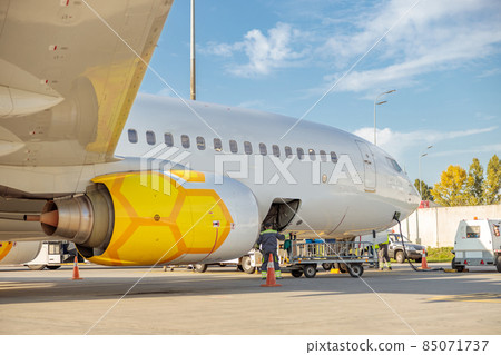 Male worker loading luggage in plane at airport Male worker loading luggage in plane at airport 85071737