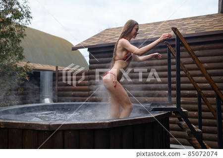 Young woman wearing bikini bathing in vat 85072074