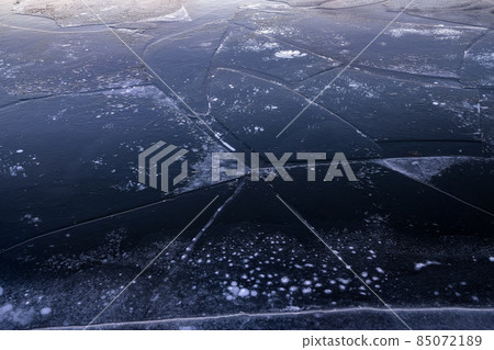 Shiny, glossy ice with cracks. Frozen river on a winter day. 85072189