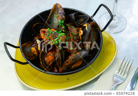 Stewed mussels in gravy with fresh chopped scallions Stewed mussels in gravy with fresh chopped scallions 85074228