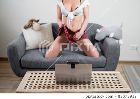 A young woman dressed in a schoolgirl costume is engaged in virtual sex on a laptop. The web model gets naked for the camera A young woman dressed in a schoolgirl costume is engaged in virtual sex on a laptop. The web model gets naked for the camera 85075912