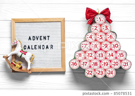 Felt board, advent calendar in shape of Christmas tree with numbers and ribbon instead of star on white wooden table Xmas advent calendar concept Top view Flat lay Holiday card 85078531