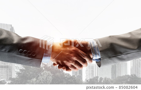 Business handshake as idea for unity and cooperation or greeting. Mixed media 85082604