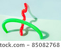 The curved pop tube stands leaning against the wall. Modern still life with antistress toy 85082768