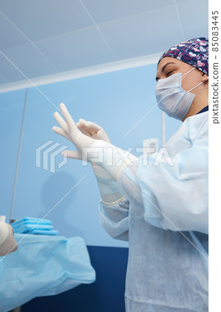 Close-up of a female surgeon in an operating room, a doctor with a tense expression on his face, in an operating room. Close-up of a female surgeon in an operating room, a doctor with a tense expression on his face, in an operating room. 85083445