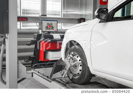 Tire clamped with aligner undergoing auto wheel alignment in garage. Tire clamped with aligner undergoing auto wheel alignment in garage. 85084420