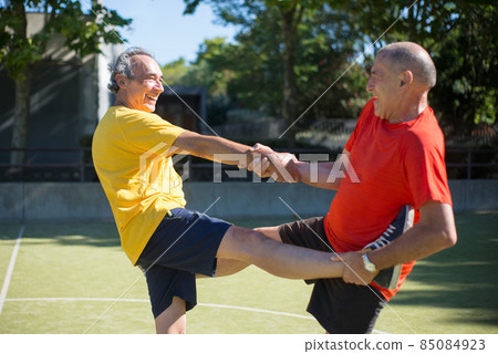 Helpful senior men getting ready for match on sunny day Helpful senior men getting ready for match on sunny day 85084923