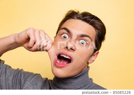 Studio shot of young handsome crazy man, student having fun, making face isolated on yellow studio background. Studio shot of young handsome crazy man, student having fun, making face isolated on yellow studio background. 85085226