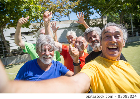 Cheery senior man taking selfie on football field 85085824