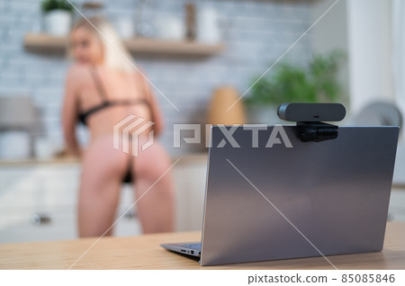 A girl in underwear flirts on an online video connection on a laptop. Woman working as a web cam model A girl in underwear flirts on an online video connection on a laptop. Woman working as a web cam model 85085846