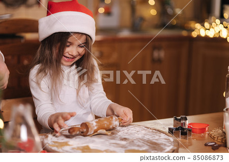 Making gingerbread at home. Little girl cutting cookies of gingerbread dough. Christmas and New Year traditions concept. Christmas bakery. Happy holidays 85086873