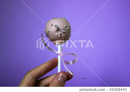 Pink chocolate round cake pops on a stick on a purple background. A sweet treat. 85088443