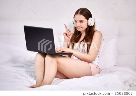 Videoconference for woman who is sitting in bed with laptop. 85088802